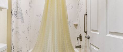 A bathroom with a bathtub, a shower curtain, and a toilet.