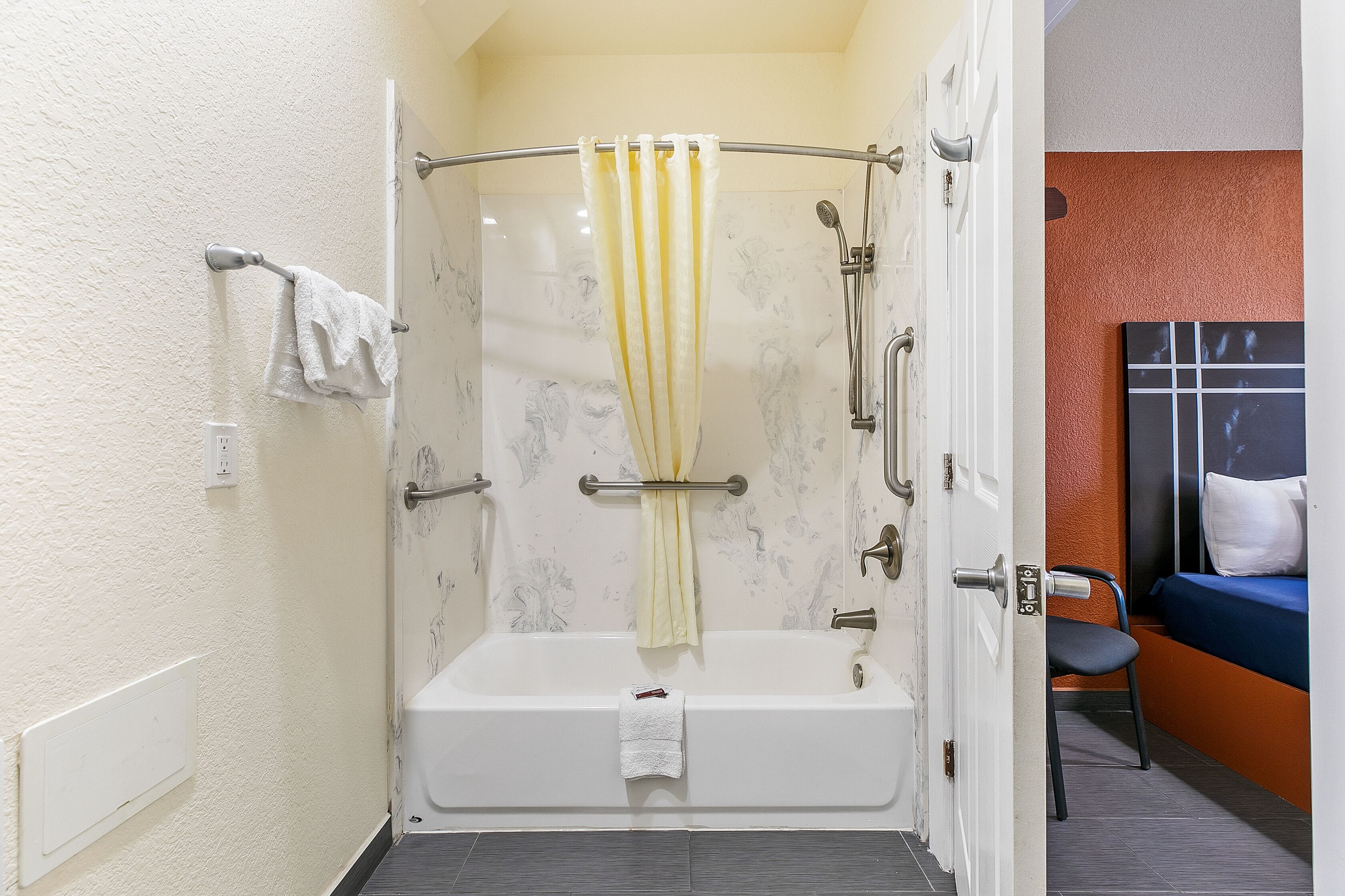 A bathroom with a bathtub, a shower curtain, a towel rack, a showerhead, and a toilet.