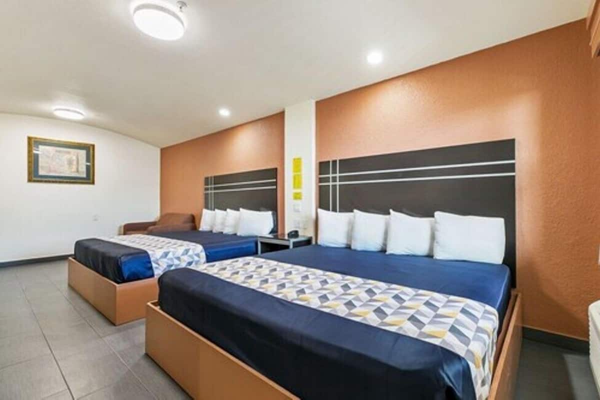 A hotel room with two beds, a small seating area, and a framed picture on the wall.