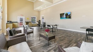 A spacious living area with wicker furniture, a glass coffee table, and artwork on the walls. - Lighthouse Inn (South Padre Island)