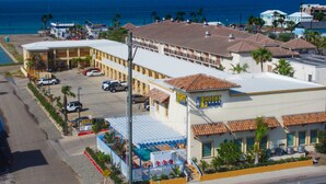 A hotel with a pool area, a parking lot, and a view of the ocean. - Lighthouse Inn (South Padre Island)