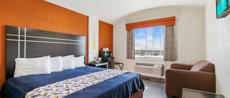 Een hotelkamer met een groot bed, een bureau, een stoel en een televisie.