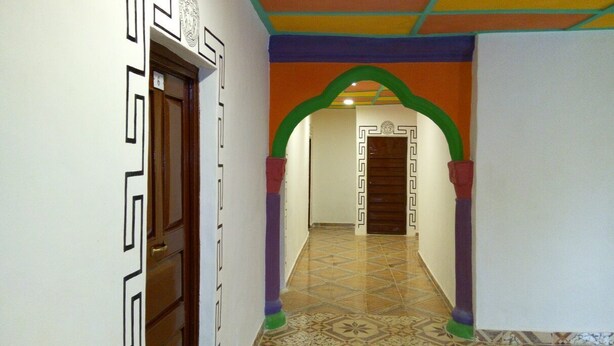 A hallway with patterned walls, a wooden door, and a tiled floor. - WS Diamond Hotel of Kono (Koidu Town)