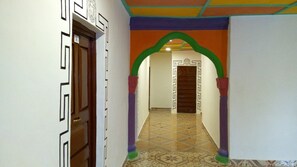 A hallway with patterned walls, a wooden door, and a tiled floor. - WS Diamond Hotel of Kono (Koidu Town)