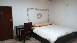Quarto com cama, escrivaninha e cadeira.