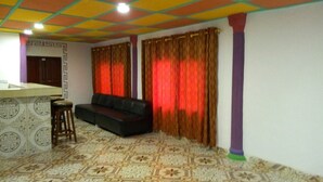 A living room with a sofa, a small stool, patterned carpet, and curtains. - WS Diamond Hotel of Kono (Koidu Town)