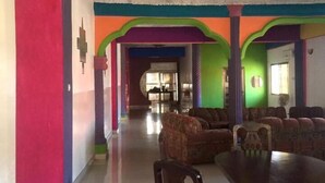 A spacious room with a large dining table and multiple chairs, a ceiling with textured design, and colorful walls. - WS Diamond Hotel of Kono (Koidu Town)