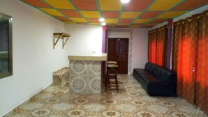 A living room with a patterned floor, a black sofa, a small wooden table, and a patterned wall. - WS Diamond Hotel of Kono (Koidu Town)