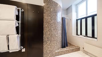 Une salle de bain moderne équipée d’une douche, d’un porte-serviettes et d’une fenêtre laissant entrer la lumière naturelle.