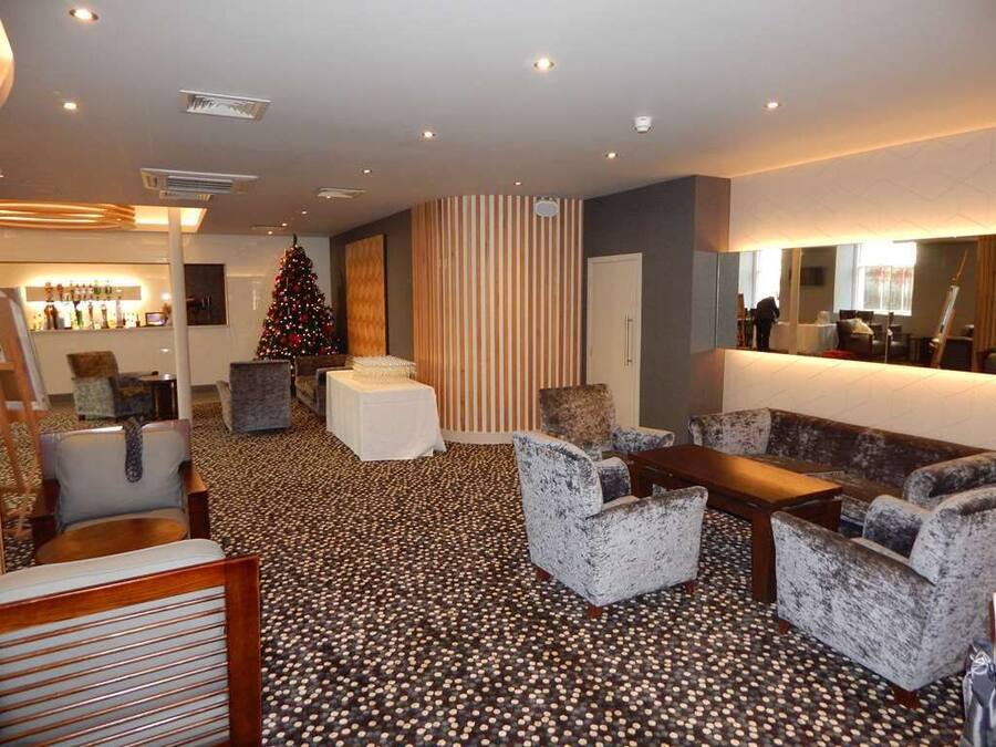 A hotel lobby with a Christmas tree, seating area, and a reception desk.