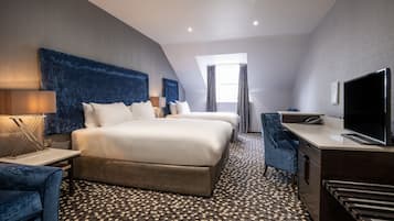 Une chambre d’hôtel moderne avec un grand lit, un bureau, une télévision et un sol à motifs.