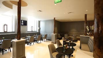 A spacious lobby with multiple seating areas, including a bar and a seating area with a fireplace.