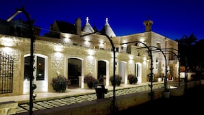 A stone building with arched doorways and a tiled entrance. - La Corte dell'Astore (Alberobello)