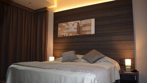 Cama bem arrumada com cobertura acolchoada, duas almofadas e uma luminária de cabeceira em um criado-mudo.