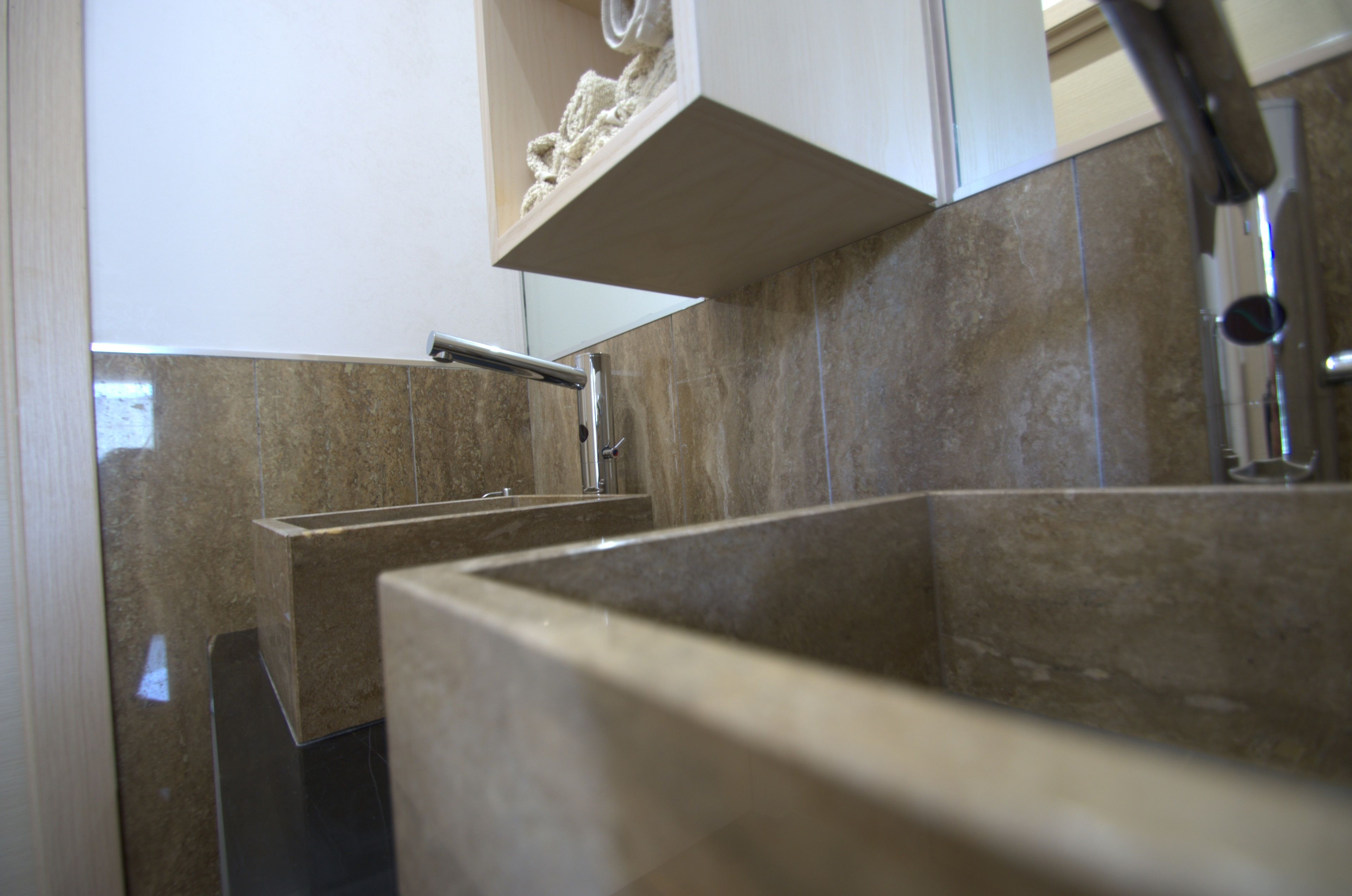 A modern bathroom with a large sink, a mirror, and a towel rack.