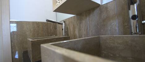 A modern bathroom with a large sink, a mirror, and a towel rack.