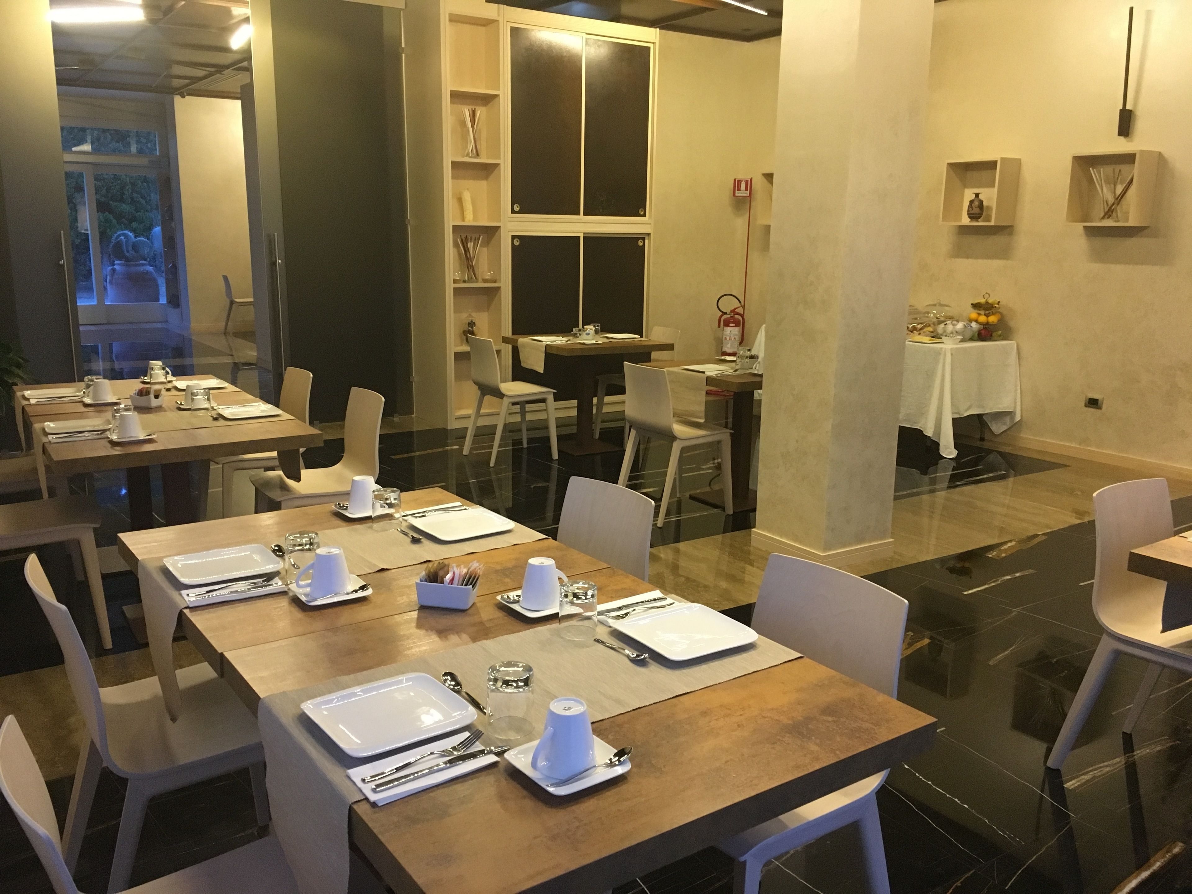 A dining area with tables set for meals, chairs, and a fire extinguisher on the wall.