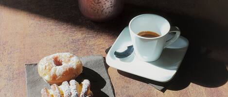 Una mesa con una taza de café, un tarro y dos pasteles.