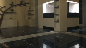 Um interior moderno com piso polido, uma escultura de árvore decorativa e um armário branco com prateleiras.