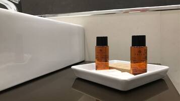 A bathroom with a white sink and two bottles of shampoo on a white tray.