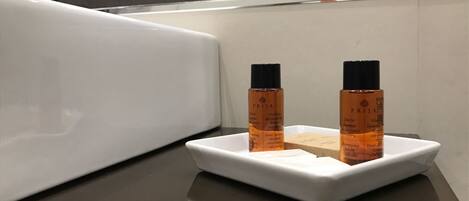 A bathroom with a white sink and two bottles of shampoo on a white tray.