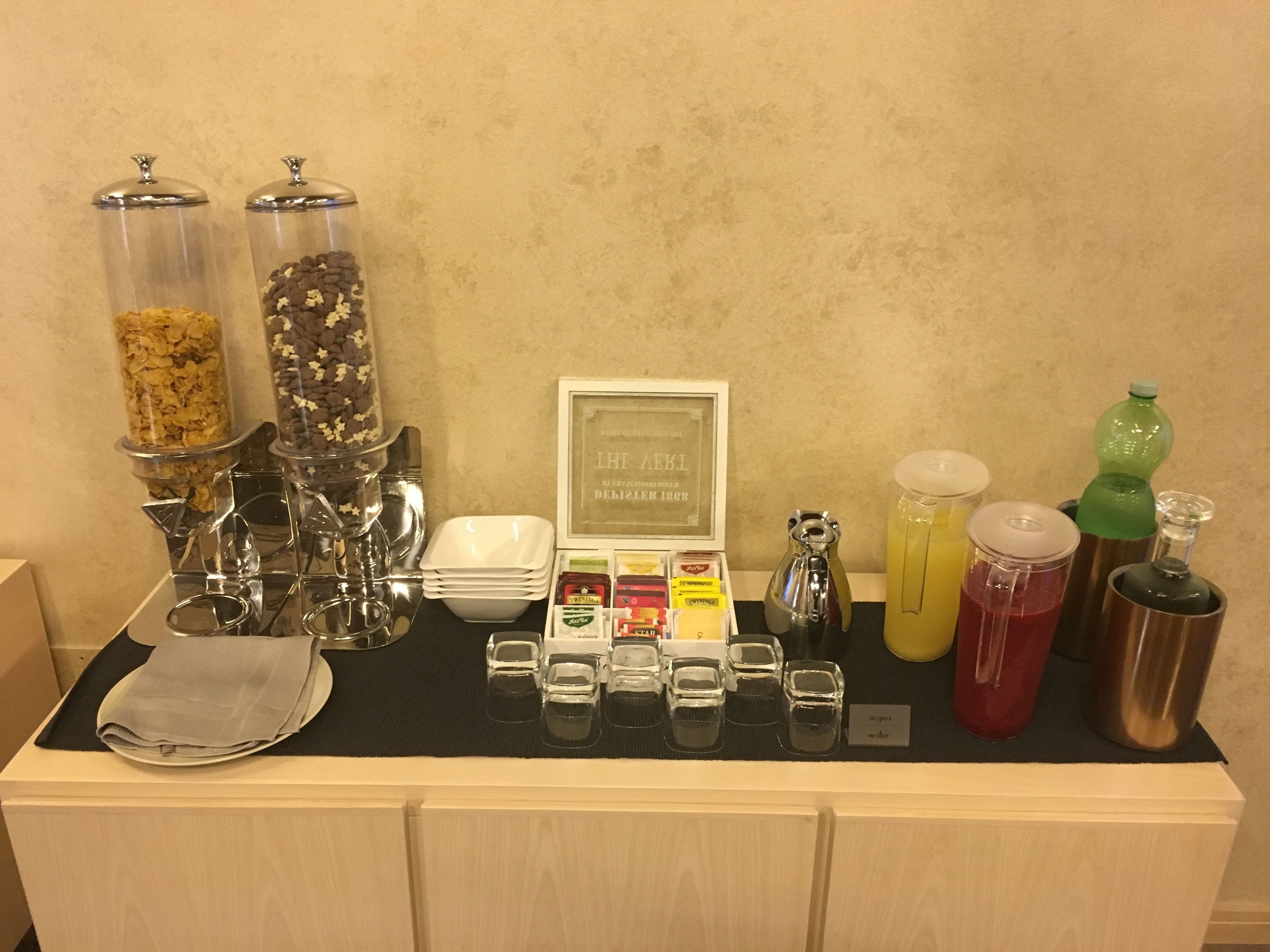 A buffet setup with various food items, condiments, and beverages.