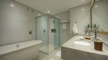 Un baño moderno con una bañera independiente, cabina de ducha con mampara de cristal y encimera de granito con lavamanos y espejo.