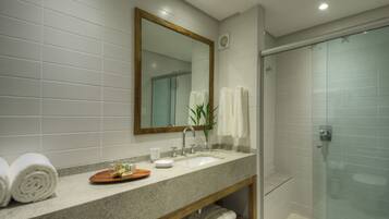 A bathroom with a granite countertop, a wooden vanity, a large mirror, a glass shower enclosure, and neatly folded towels.