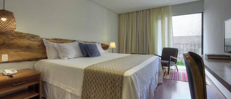 Een moderne hotelkamer met een groot bed, een nachtkastje met een lamp, een stoel en een televisie.