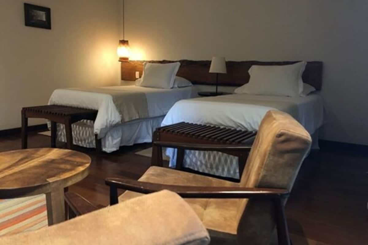 A hotel room with two beds, a small table, and a chair.