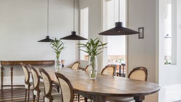 Un comedor con una gran mesa de madera, varias sillas, lámparas colgantes y piso a rayas.
