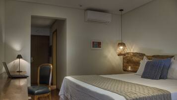Una habitación de hotel con cama, escritorio, laptop, silla y aire acondicionado de pared.