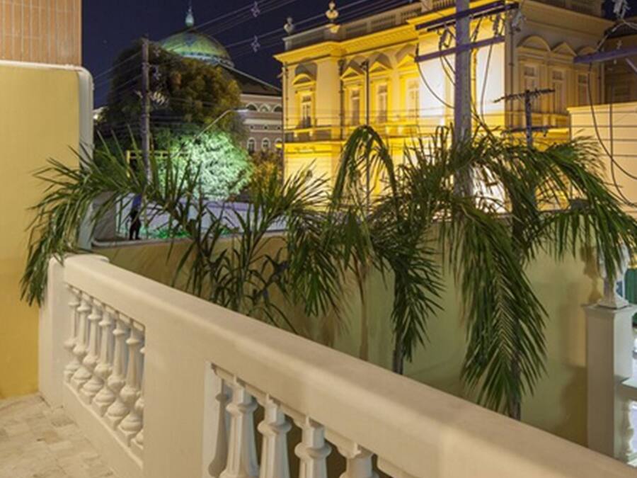 A balcony with a white balustrade overlooking a building with a green dome and yellow lighting.