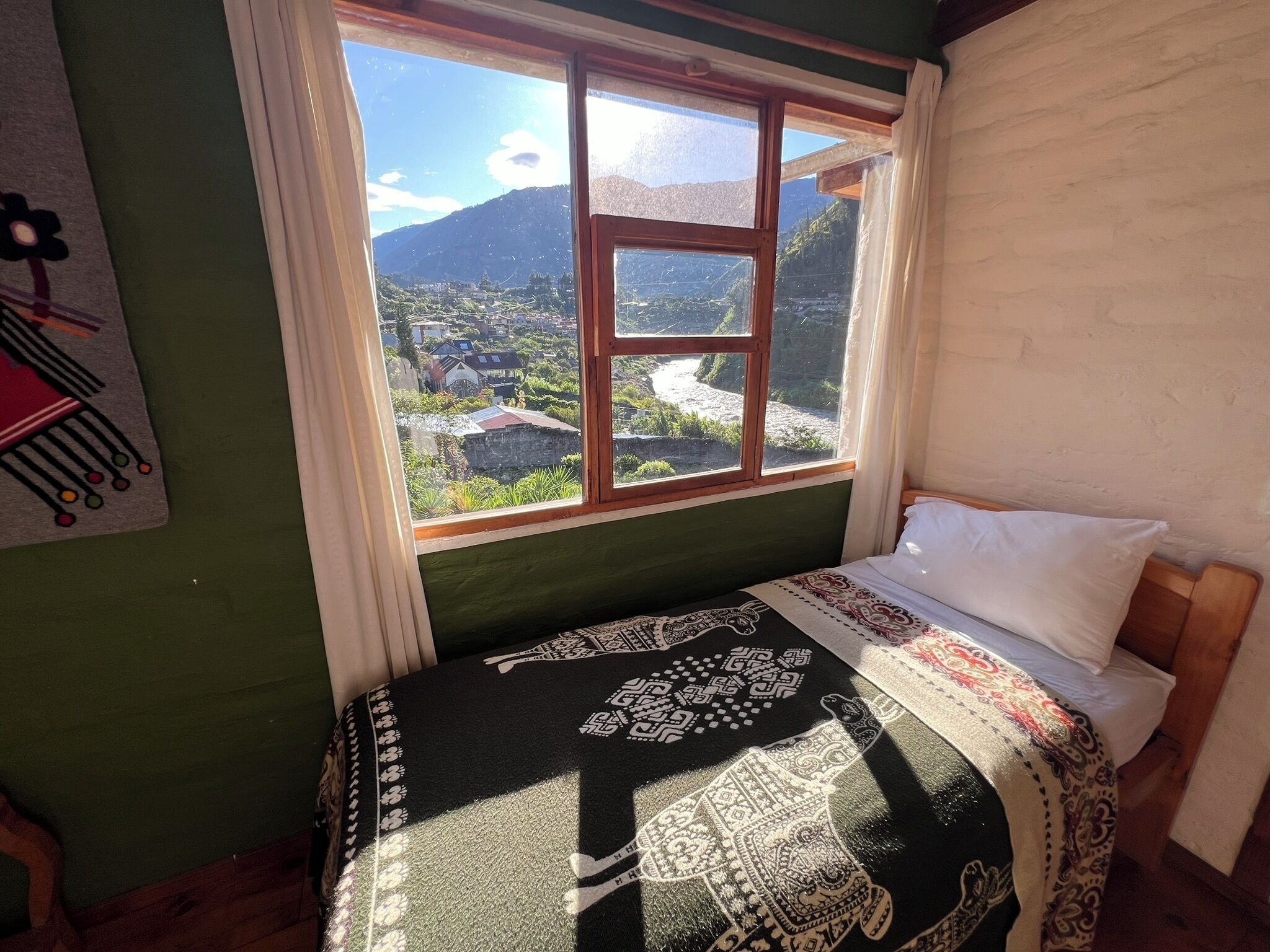 Ein Zimmer mit Bett, einem Fenster mit Blick auf eine Berglandschaft und einer Wand mit einem dekorativen Gegenstand.
