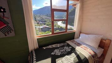 Ein Zimmer mit Bett, einem Fenster mit Blick auf eine Berglandschaft und einer Wand mit einem dekorativen Gegenstand.