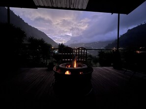 A fire pit with a view of mountains and a cityscape in the background. - La Casa Verde (Baños de Agua Santa)