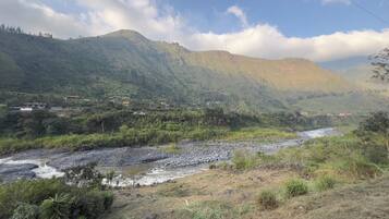 A river flowing through a valley with mountains in the background and a few scattered buildings.