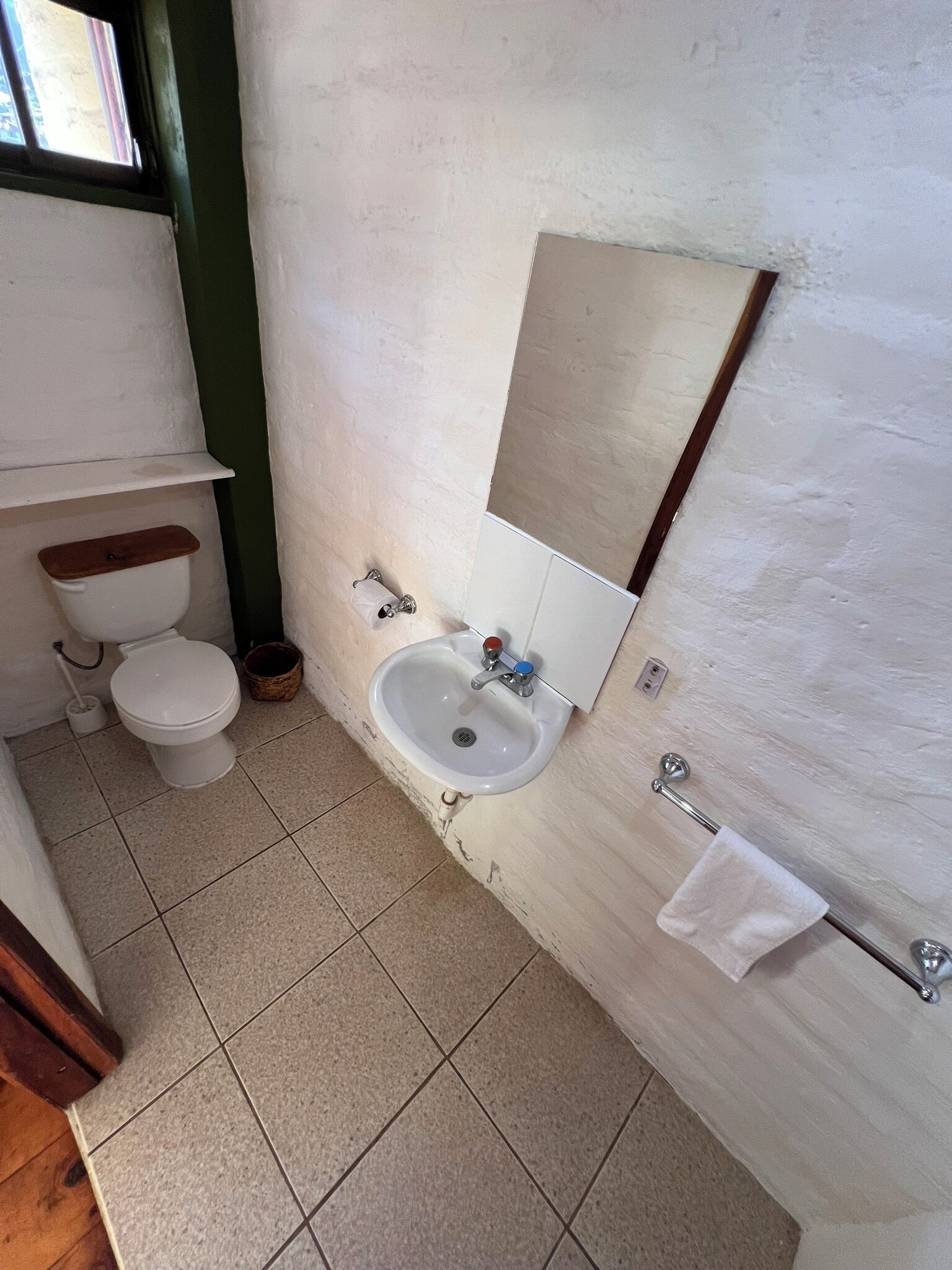A small bathroom with a toilet, sink, and mirror.