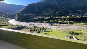 Een rivier die door een vallei stroomt, met bergen op de achtergrond en een brug in de voorgrond.