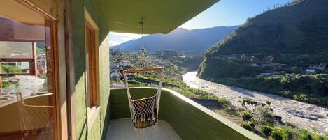 A balcony with a view of a river and mountains.