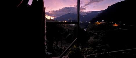 A balcony with a view of a mountainous landscape at dusk.