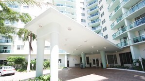 A modern hotel entrance with a covered walkway, multiple floors, and a car parked outside. - The Tides by MiaRentals (Hollywood)