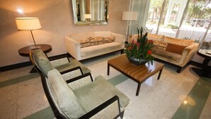 A living room with a sofa, armchairs, a coffee table, and a mirror on the wall. - The Tides by MiaRentals (Hollywood)