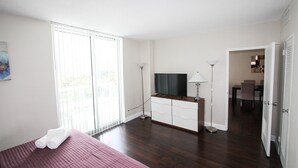 A hotel room with a bed, a desk, a chair, a TV, and a lamp. - The Tides by MiaRentals (Hollywood)