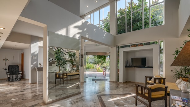 A spacious lobby with a high ceiling, large windows, and a central open area leading to a balcony. - Peli Hotel (Kissamos)