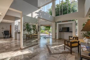 A spacious lobby with a high ceiling, large windows, and a central open area leading to a balcony. - Peli Hotel (Kissamos)