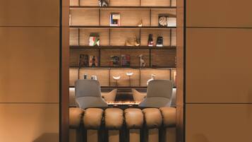 A modern interior with a fireplace, leather seating, and a wooden bookshelf with various decorative items.
