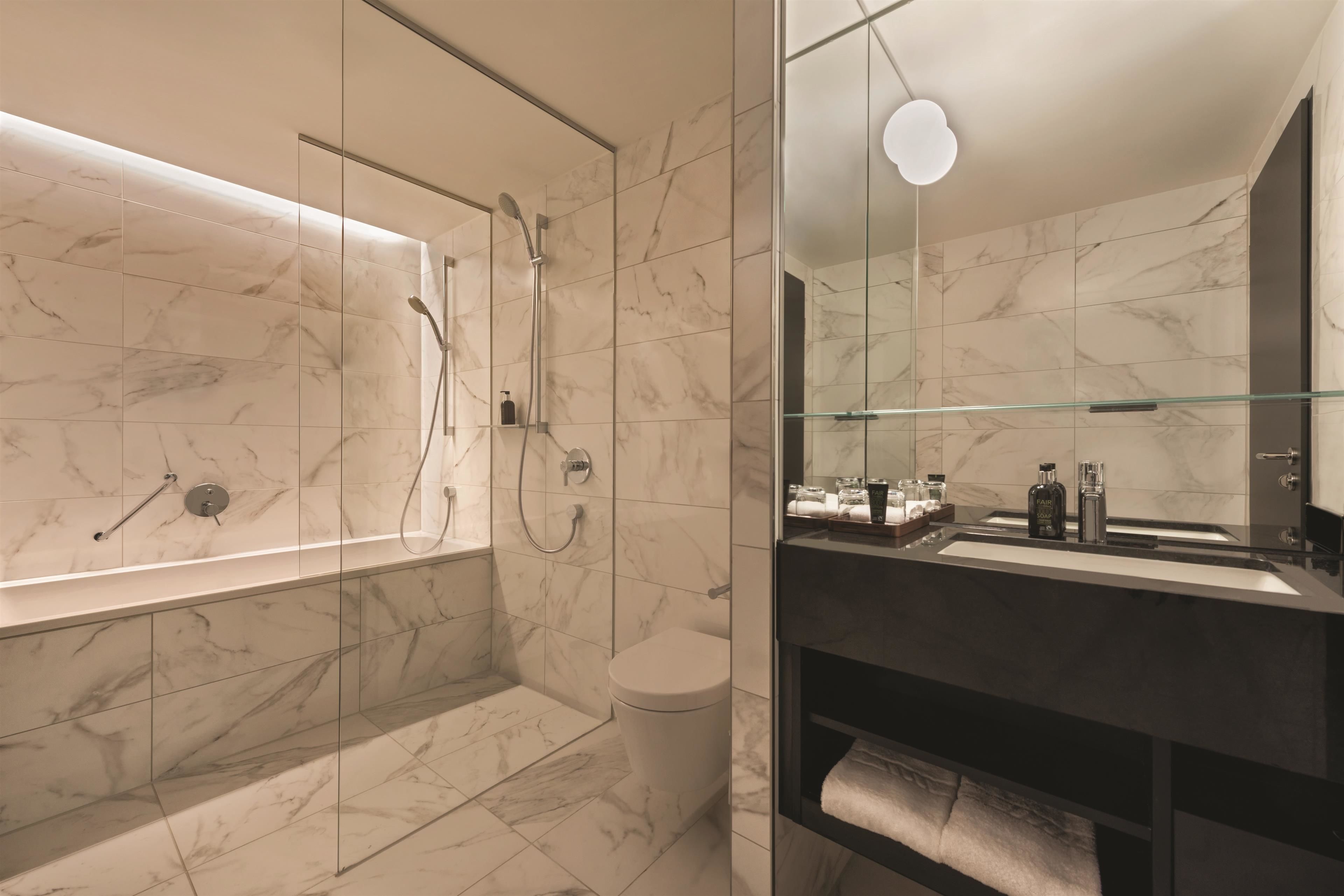Une salle de bain moderne avec une douche à parois de verre, des toilettes et un meuble-lavabo avec un miroir.