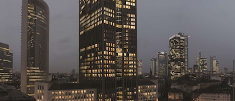 A cityscape at dusk with illuminated high-rise buildings.