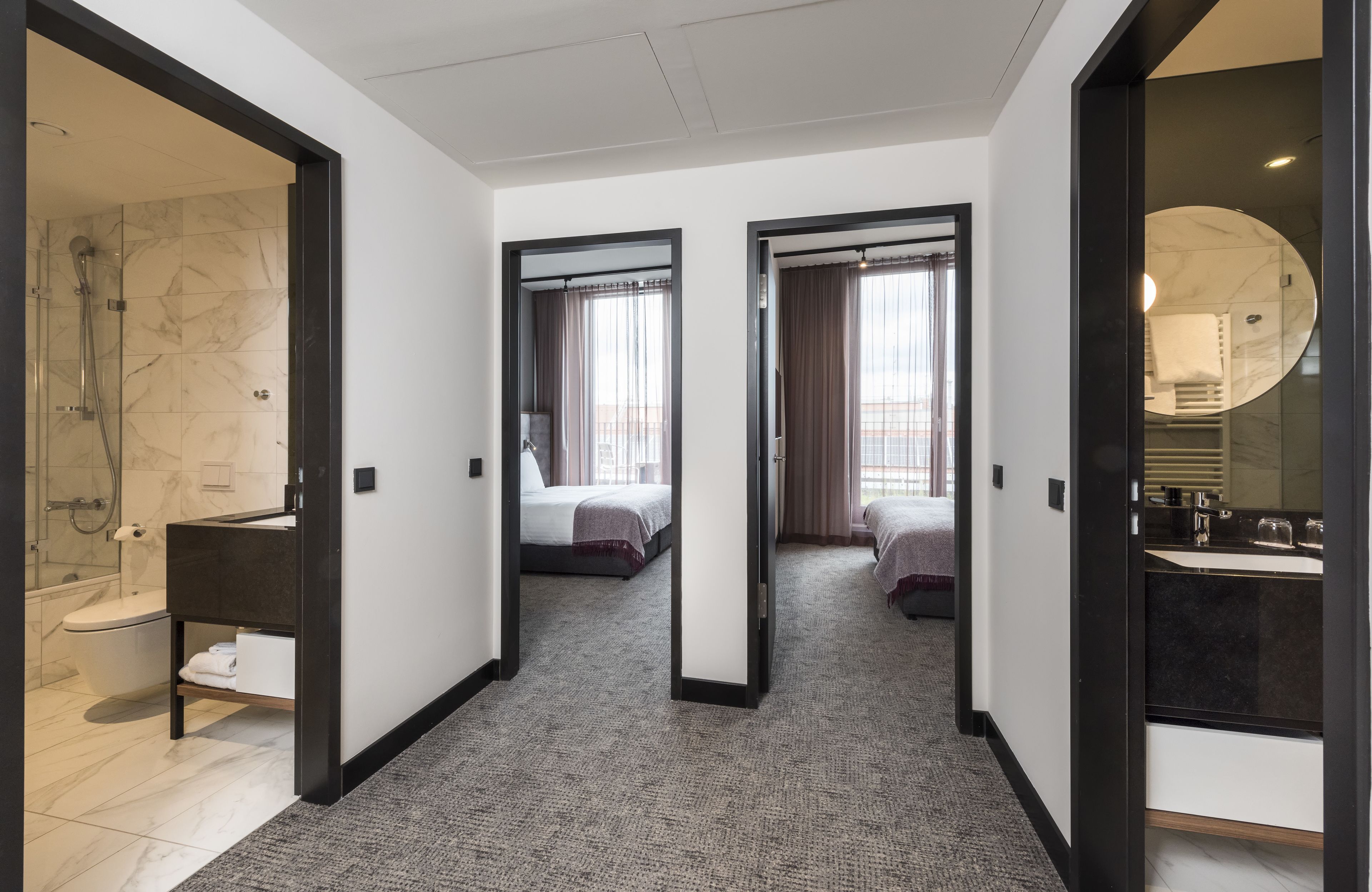 A modern hotel room with a bathroom, a bed, and a large mirror.